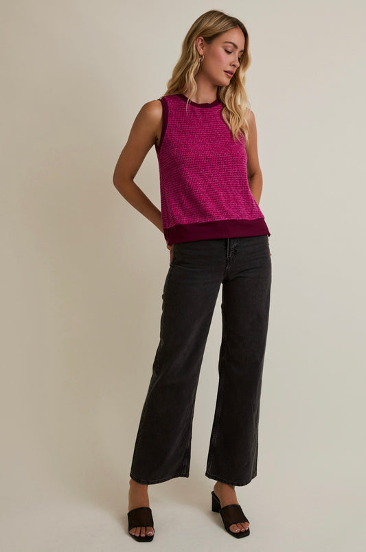 Woman wearing a pink sleeveless top and black pants on a beige background