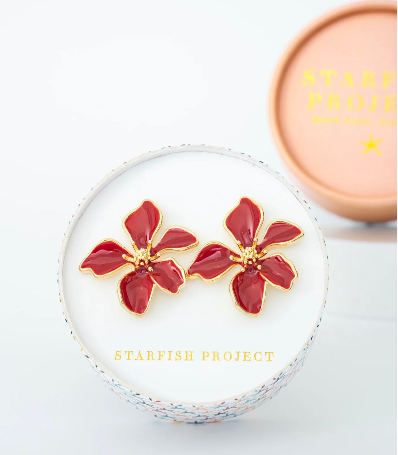 Red floral earrings in a white display case with 'Starfish Project' branding.