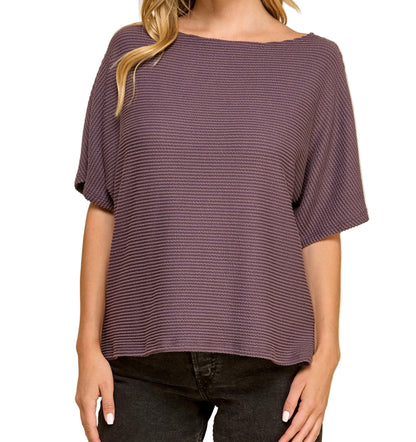 Woman wearing a purple textured top against a white background