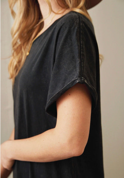 Person wearing a black t-shirt against a neutral background