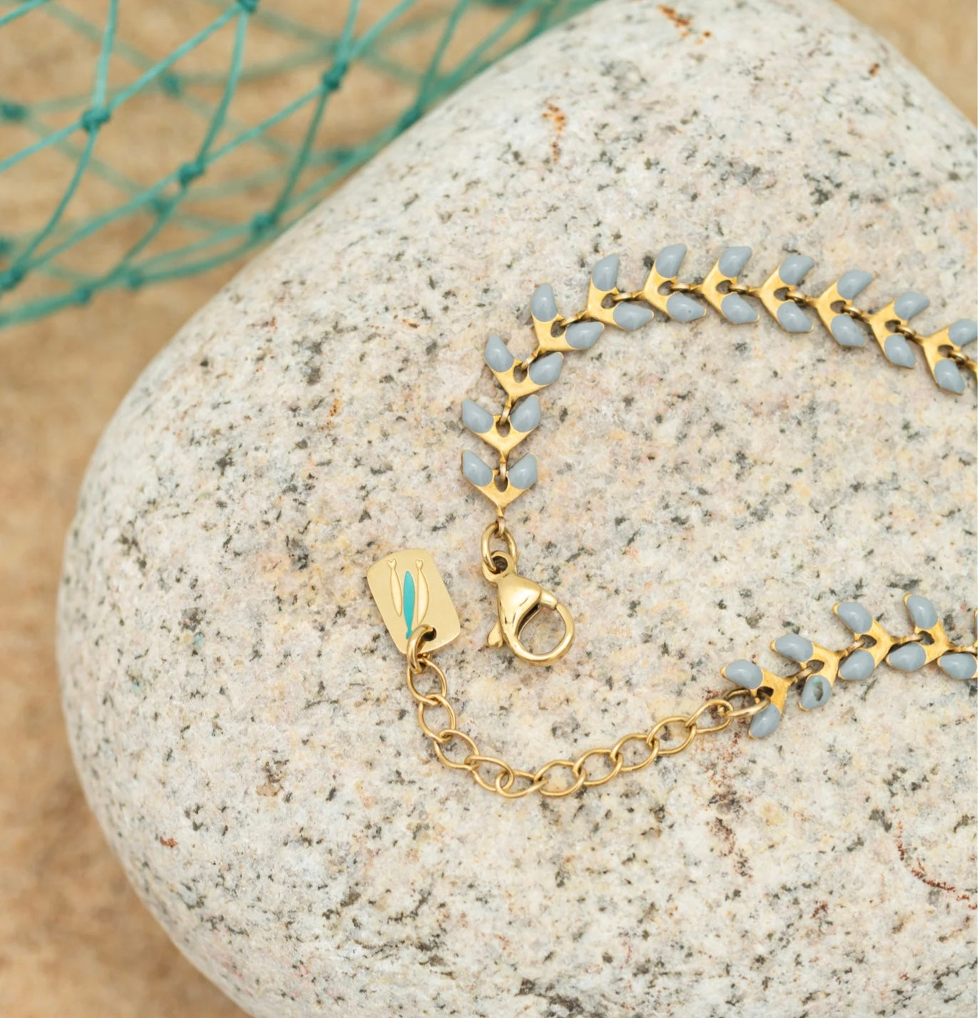 Gold bracelet with blue contrast enamel on a textured stone surface