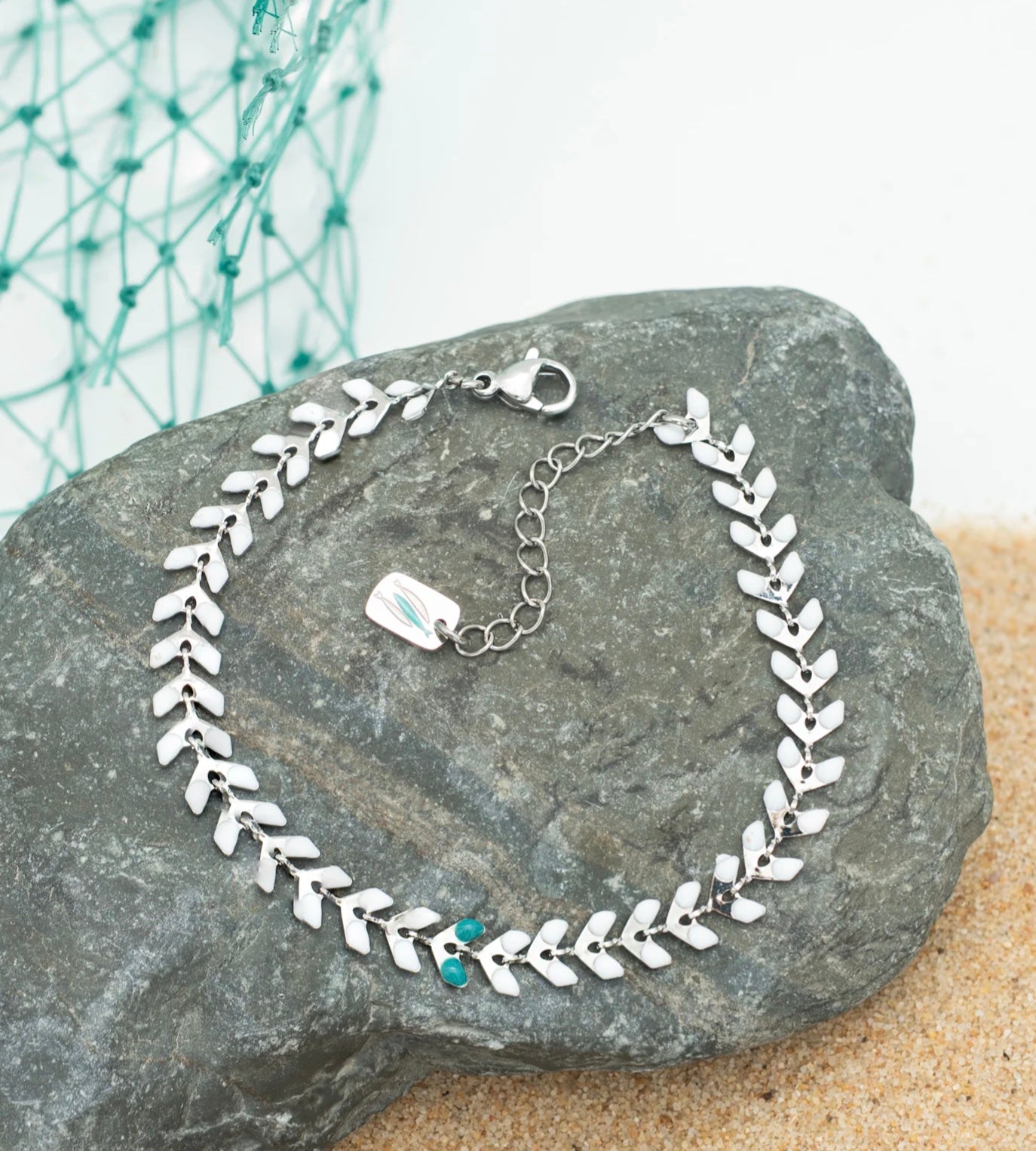 Silver leaf bracelet inspired by The Chosen on a stone surface with a blurred green net in the background