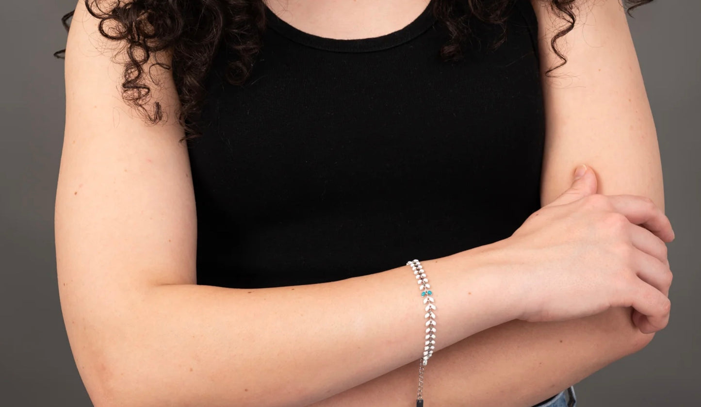 Person wearing a black top with the silver bracelet on a neutral background
