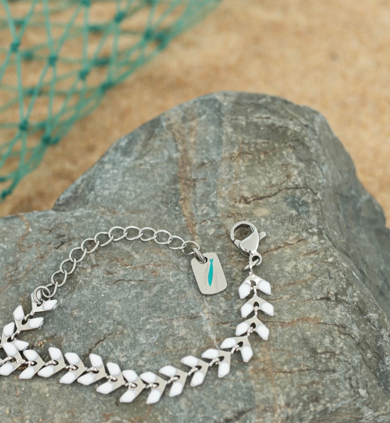 Silver bracelet with leaf-like designs on a rock