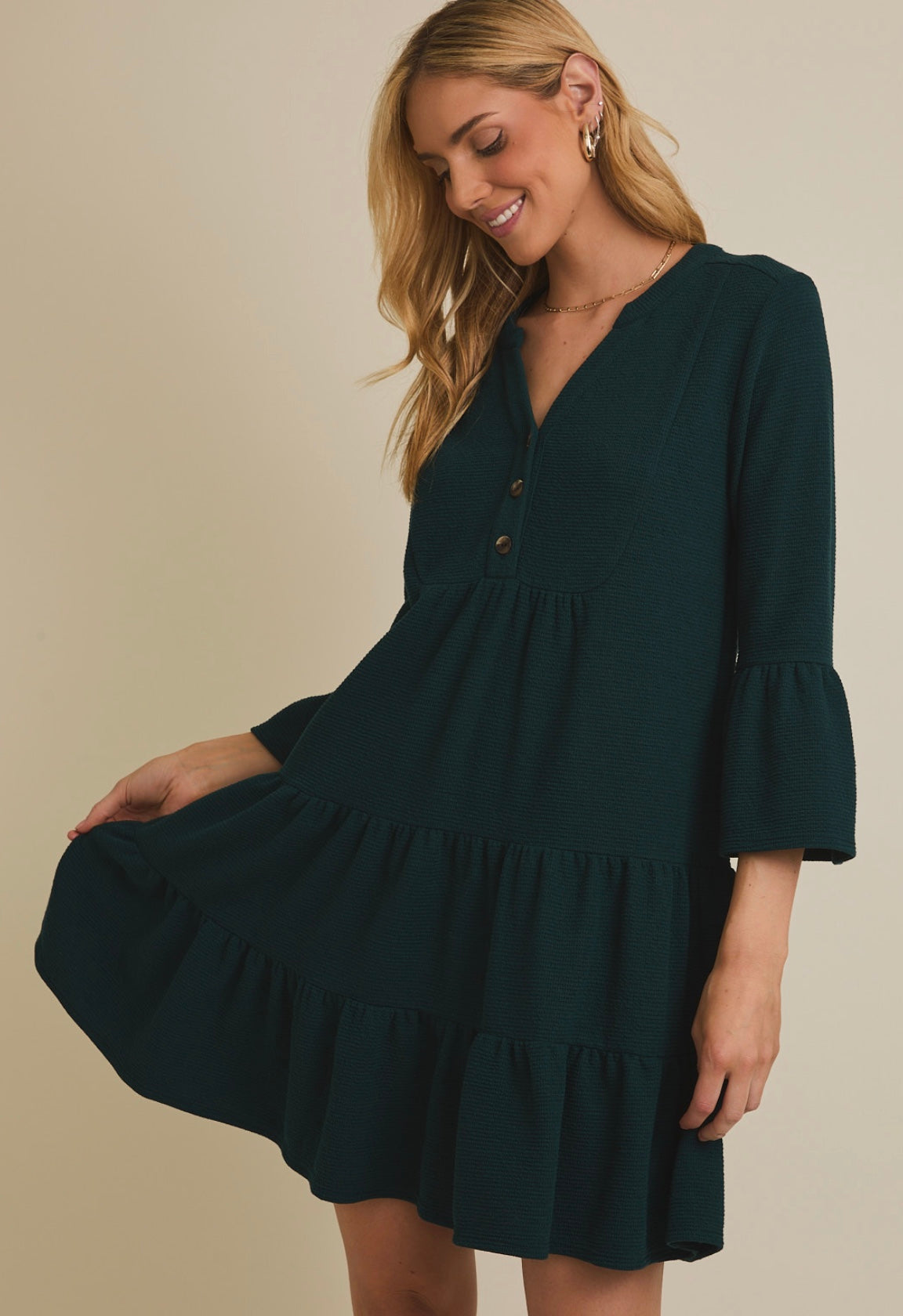 Woman wearing a dark green dress with a plain background