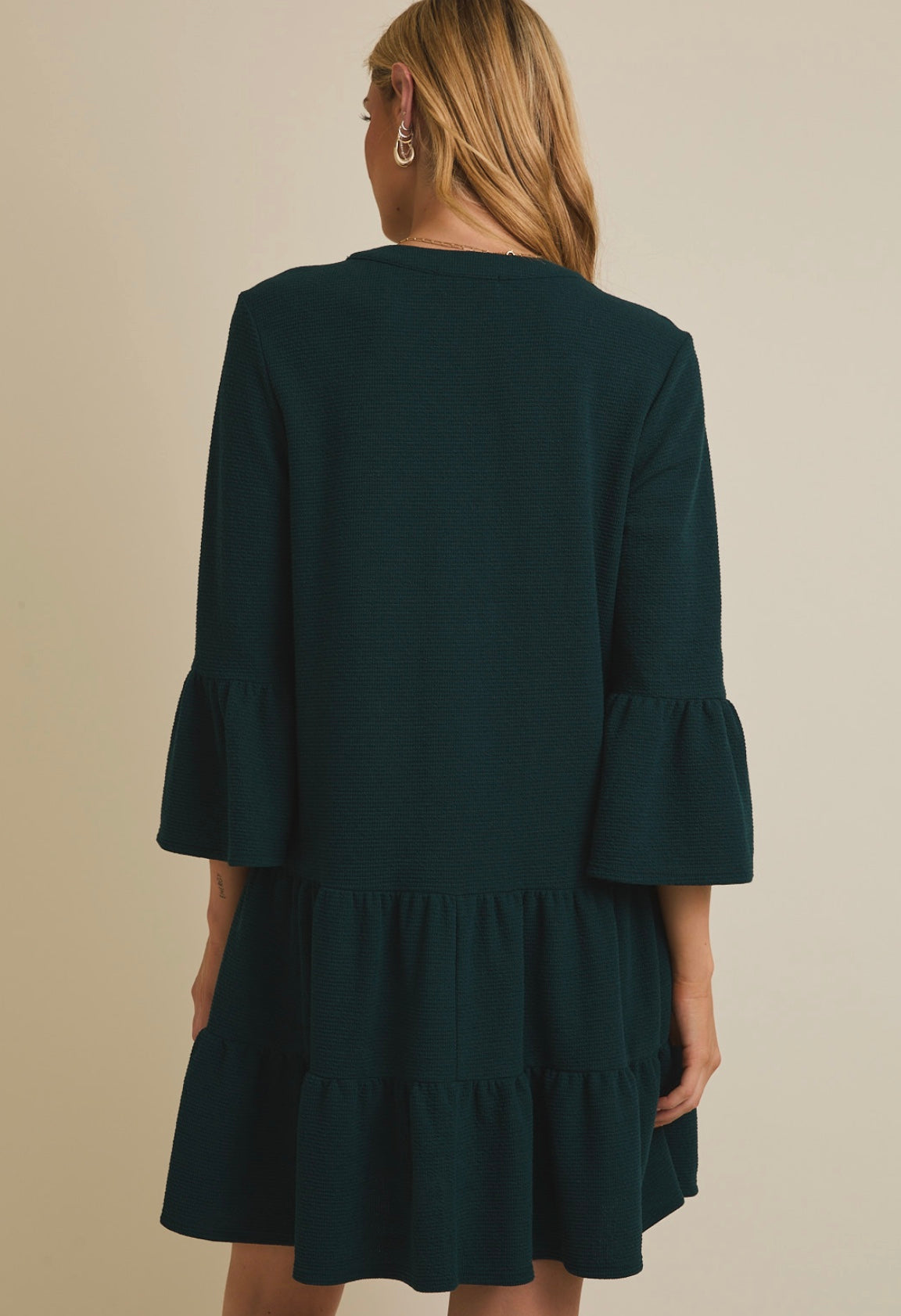 Green dress with ruffled sleeves worn by a person on a beige background