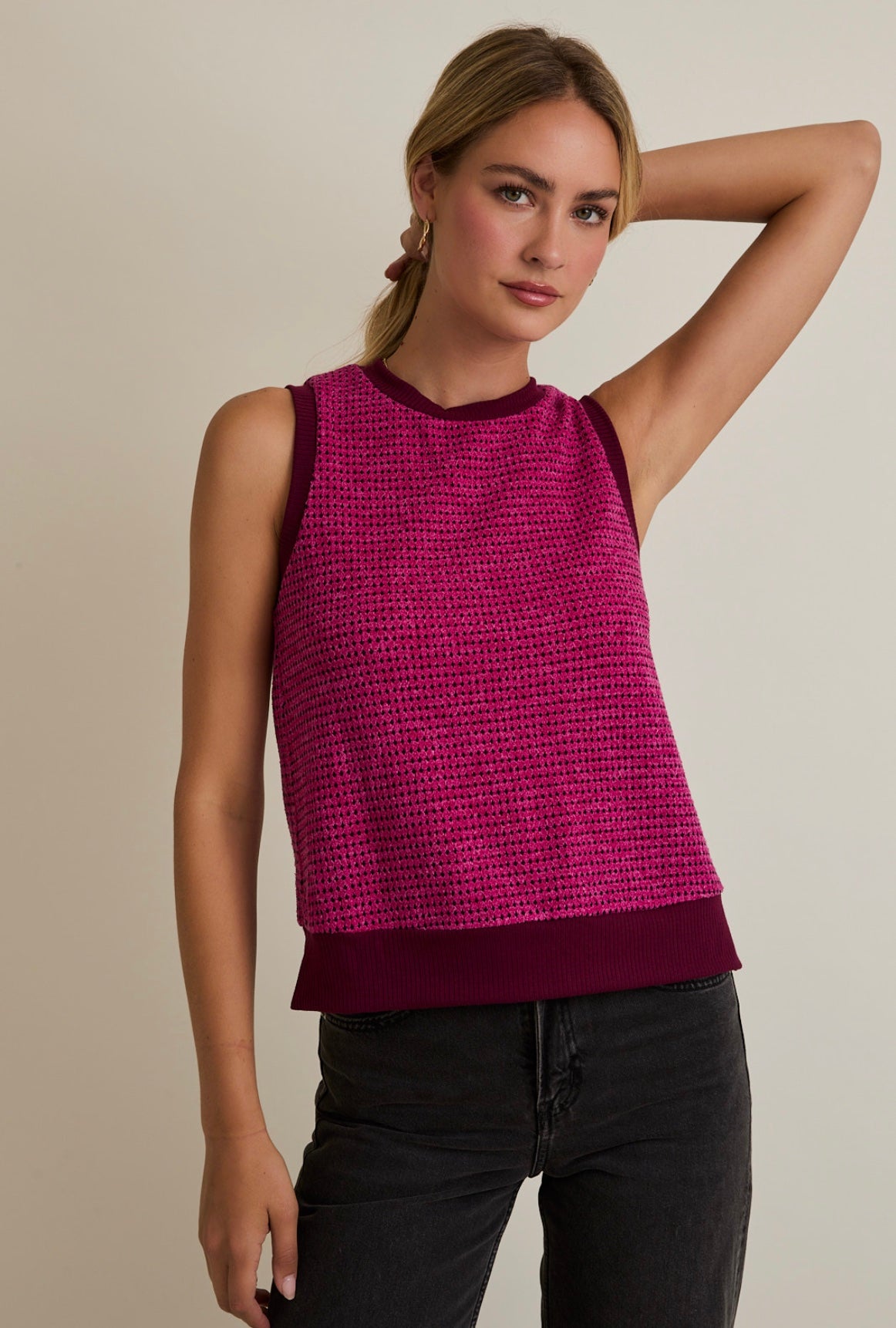 Woman wearing a sleeveless magenta top with a beige background