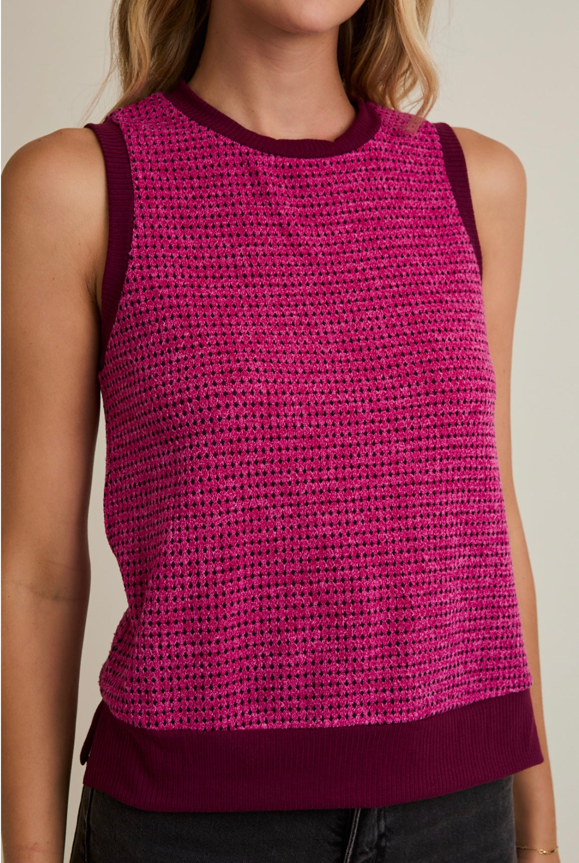 Person wearing a pink knitted tank top with a blurred background