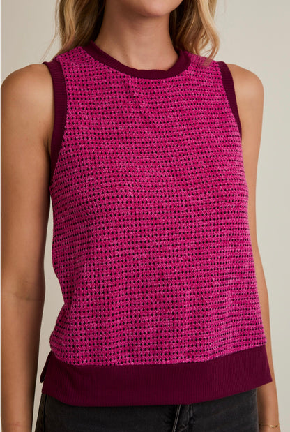 Person wearing a pink knitted tank top with a blurred background