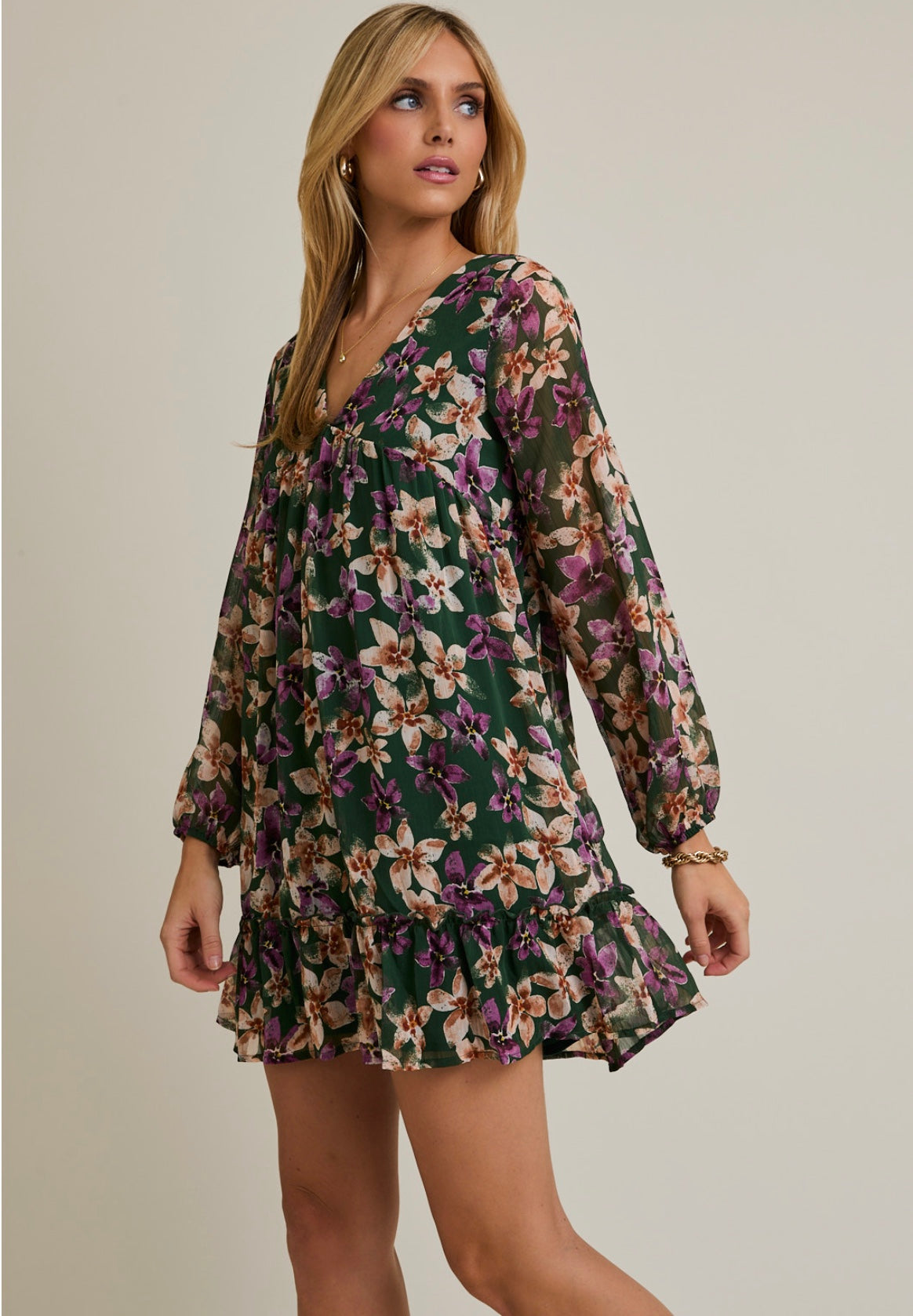 Woman wearing a floral dress with long sleeves on a neutral background