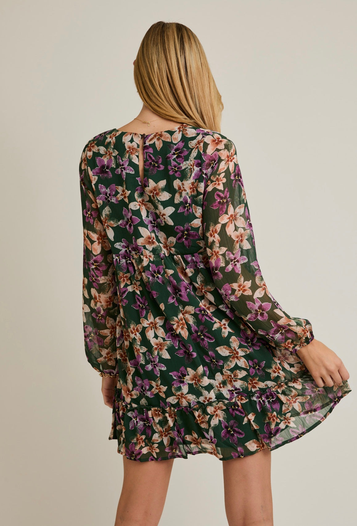 Woman wearing a floral dress with long sleeves on a plain background