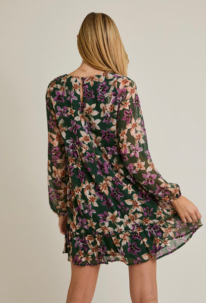 Woman wearing a floral dress with long sleeves on a plain background