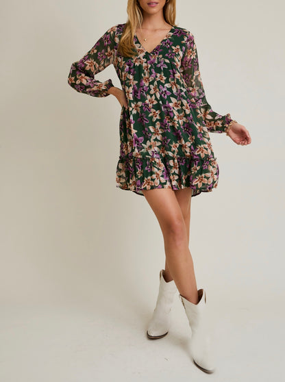 Woman wearing a floral dress with long sleeves and white boots on a plain background