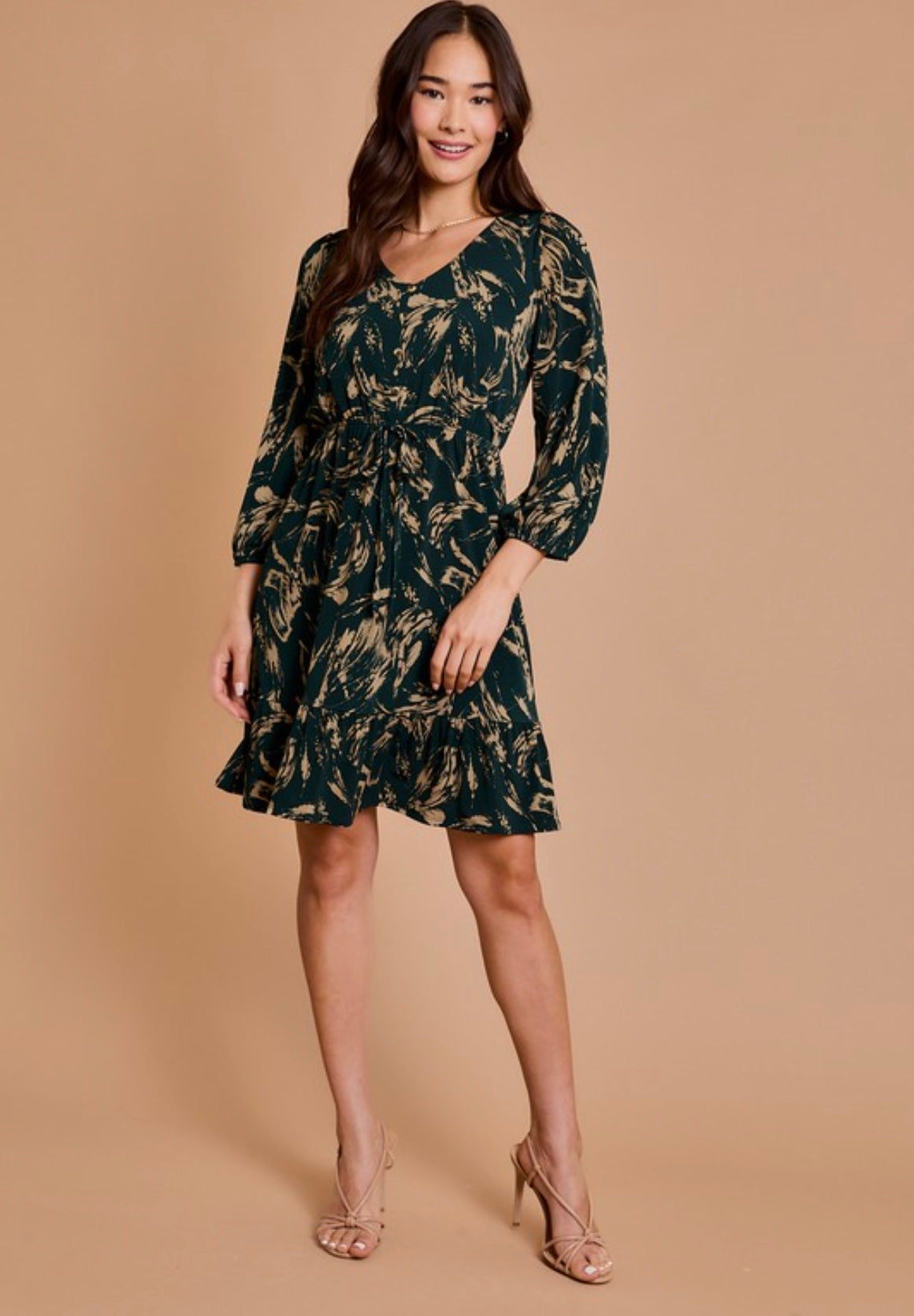 Woman wearing a dark green floral dress against a beige background