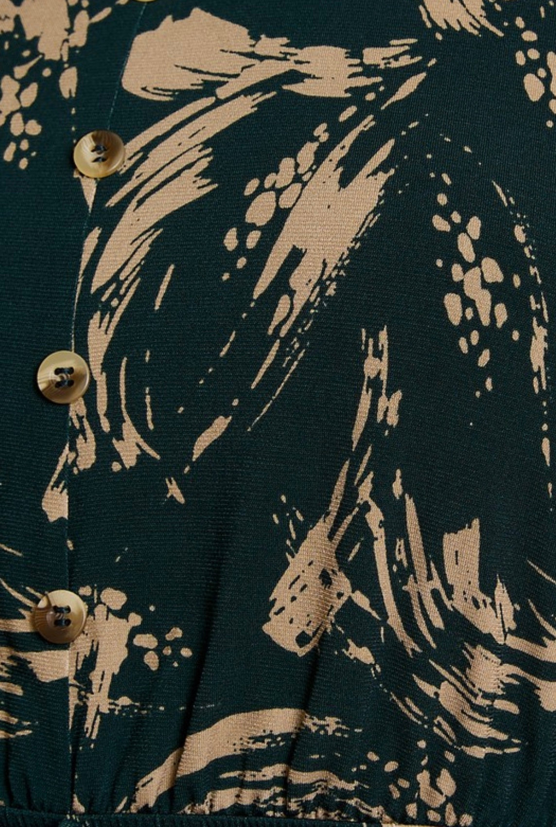 Close-up of a dark fabric with beige abstract patterns and buttons.