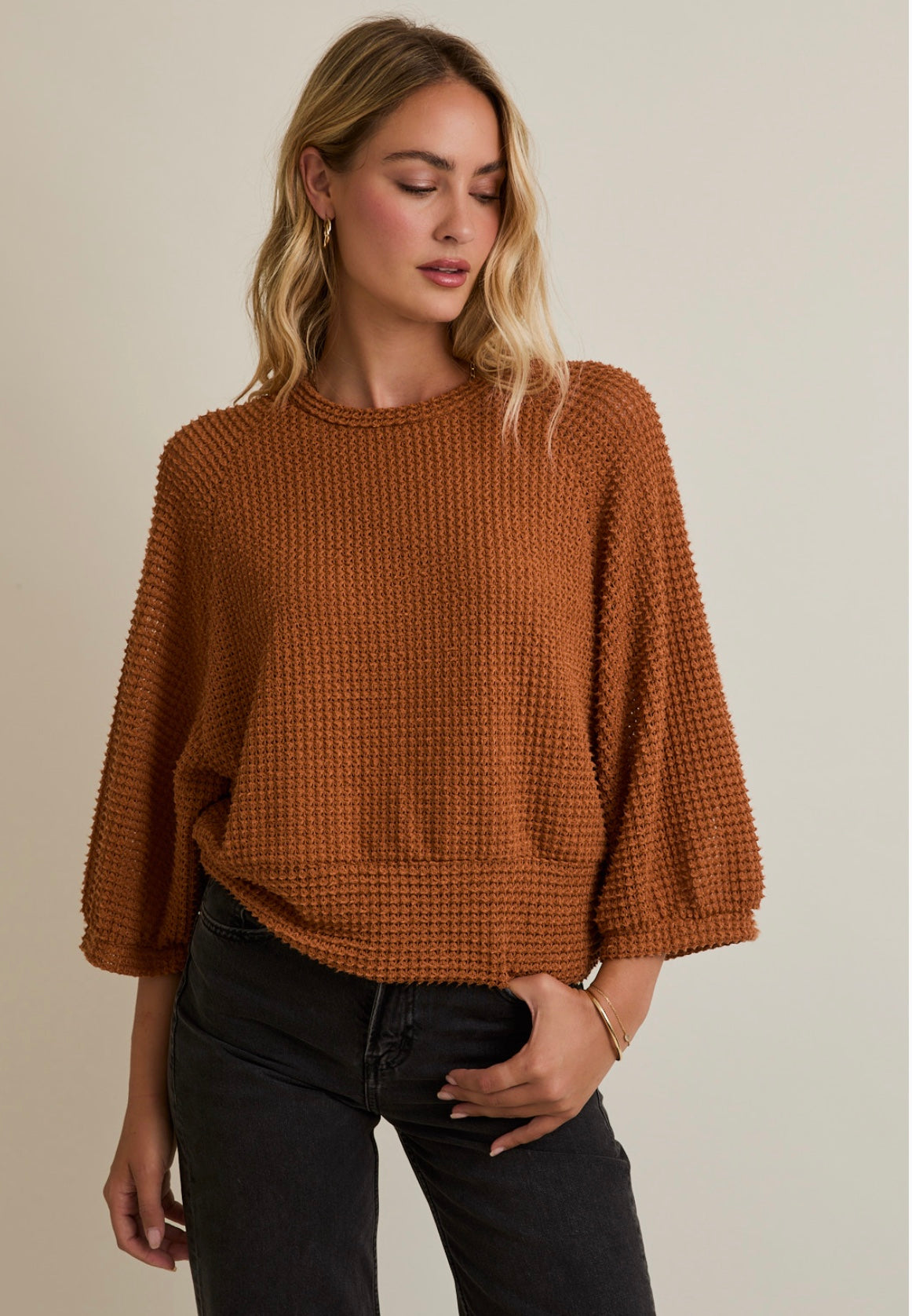 Woman wearing a brown knitted sweater against a neutral background