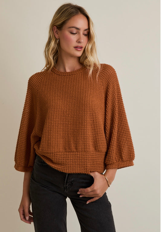 Woman wearing a brown knitted sweater against a neutral background