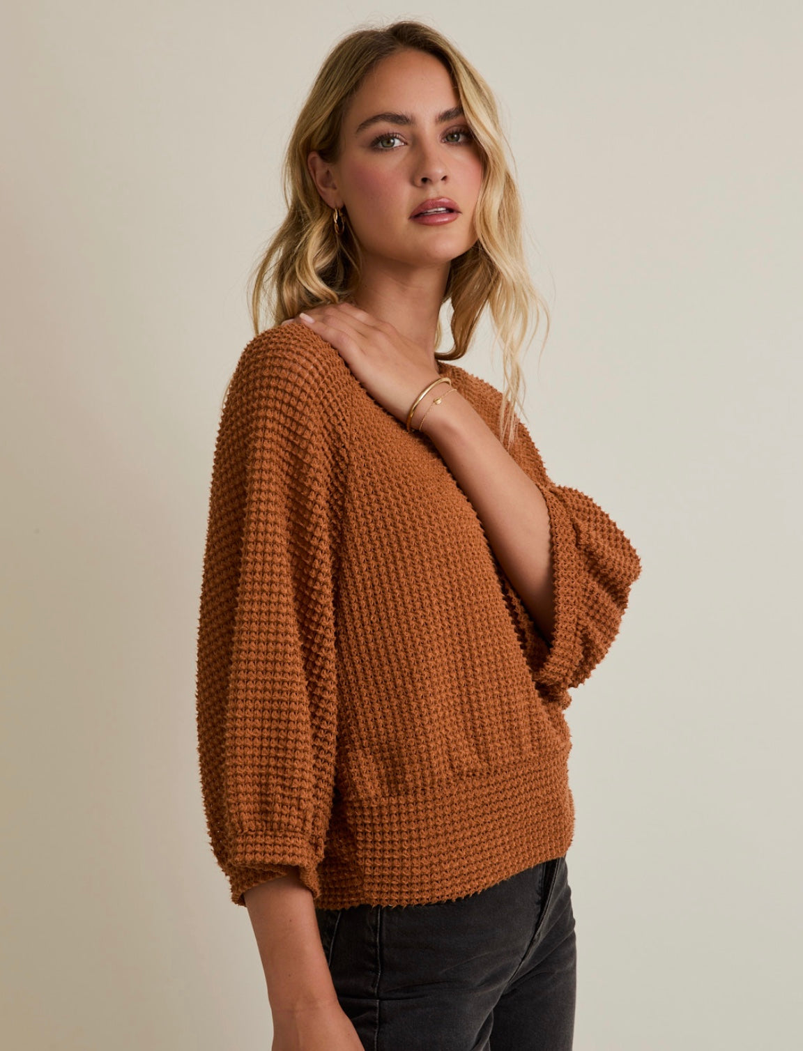 Woman wearing a brown knitted sweater against a beige background