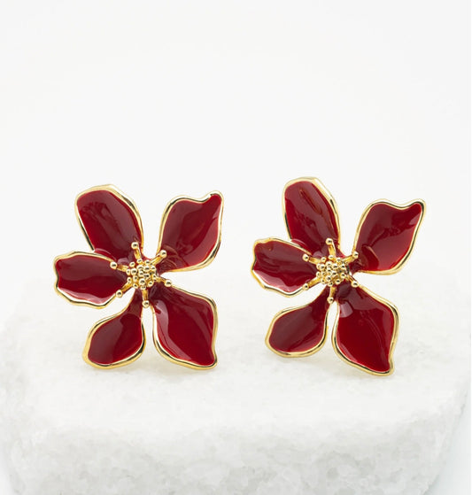 Red flower-shaped earrings with gold accents on a white background